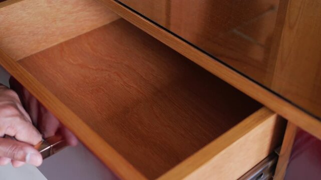Close up shot of a hand opening wooden drawer of cabinet furniture
