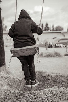 Lonely child on a swing in a somber black and white scene