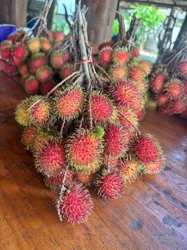 Top view of fresh sweet rambutan fruits bunch on a rustic wooden table background.