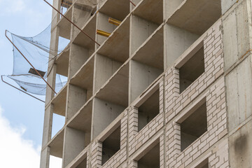Building rises against the sky as construction progresses in the bustling city center with workers busy and tools scattered around © beholdereye