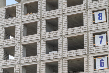 Construction of a modern building with numbered floors showcasing the progress of urban development © beholdereye