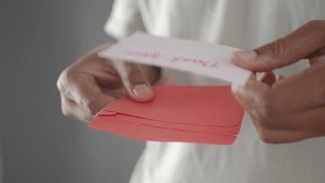 Person holding red envelope with thank you card