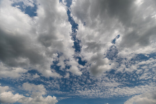 Majestic cloud formations dance across a vivid blue sky in a serene afternoon