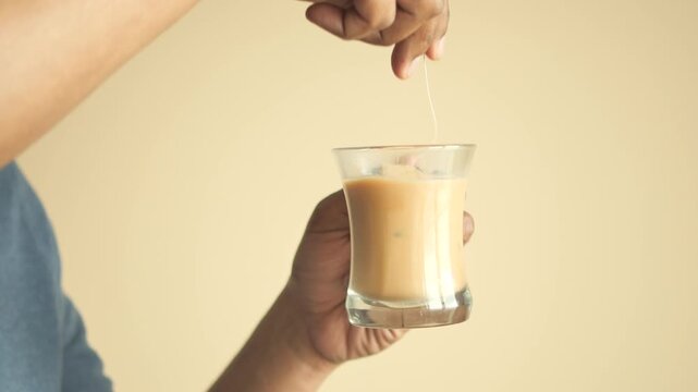 A person is making a cup of milk tea with a tea bag at home in slow motion, close-up shot