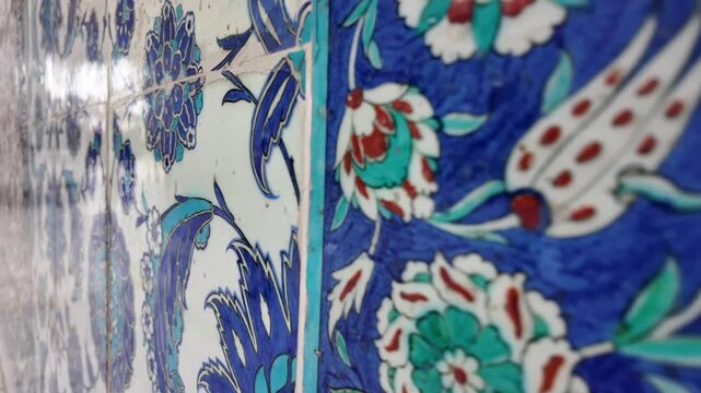 Close up camera movement showing details of historic iznik tiles on a wall, showcasing traditional ottoman floral art and intricate patterns in vivid blue, turquoise and red hues
