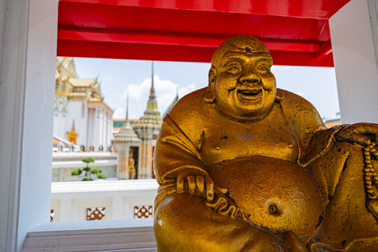 Golden smiling Laughing Buddha statue framed in Wat Pho temple