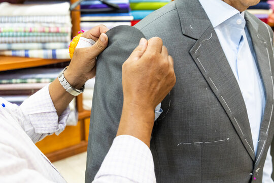 Close-up of professional tailor adjusting and refining new suit with needles to have perfect fit for client in shop before sewing and delivering perfectively fit clothing for client
