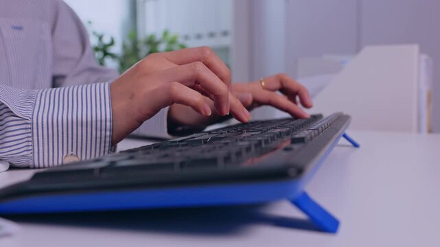 Human hand typing on computer keyboard at office desk, focused business work and digital technology activity, workplace administration with businessperson working indoors at modern office desk setup