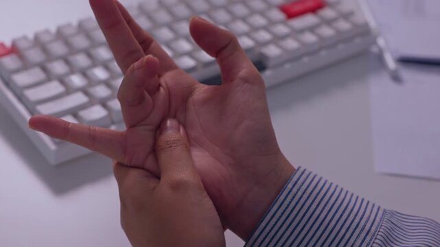 Human hand gesture with finger pressure and palm massage for wrist pain and skin strain during office keyboard work, ergonomic computer workspace showing adult hand, desk, typing, and communication