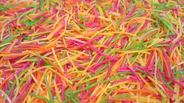 Colorful Vermicelli pasta rotating background. Dry uncooked Seviyan. Multicolored Filini pasta
