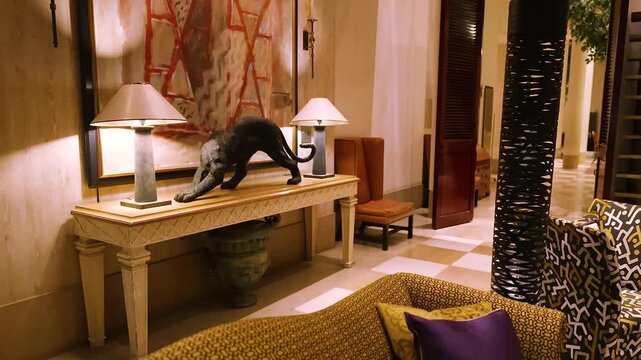 Luxurious interior design showcasing a panther statue on a console table with ornate lamps and patterned upholstery.