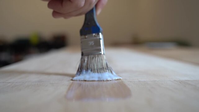 Home renovation: applying protective varnish to a wooden table with a brush