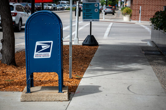 ROCHESTER, MINNESOTA - AUGUST 28, 2026: A blue United States Postal Service collection box on a sidewalk with traffic in the background.