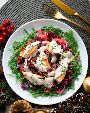 Salmon salad with beetroot, vegetables, and yogurt sauce. Overhead view. Christmas meal with festive decorations.
