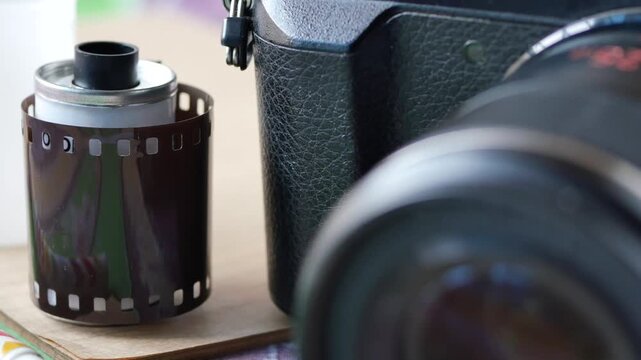 Close up of a film roll next to a vintage camera, manual focus adjustment