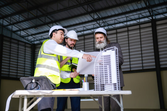 Construction manager team presented building structure process to senior management, using scale model at site with drawing paper. Concept of brainstorming in construction project management.