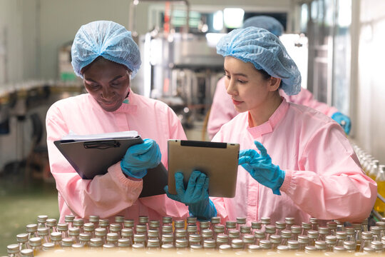 Asian and black factory worker inspect line product with tablet in beverage factory. Food and drinks Industry workers. 