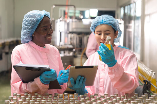 Asian and black factory worker inspect line product with tablet in beverage factory. Food and drinks Industry workers. 