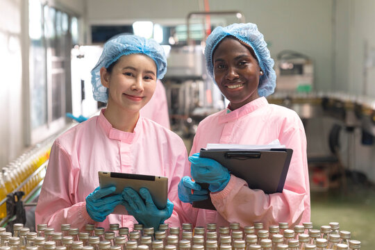 Asian and black factory worker inspect line product with tablet in beverage factory. Food and drinks Industry workers. 