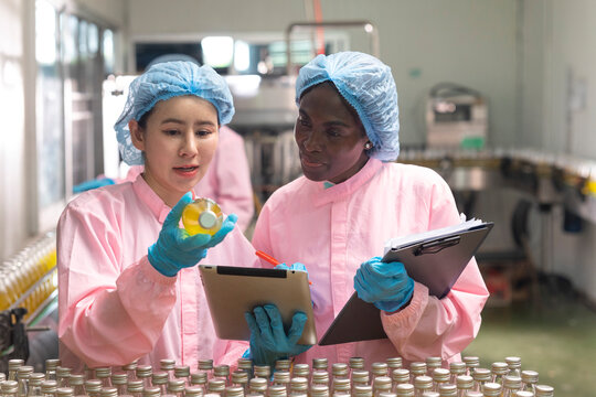 Asian and black factory worker inspect line product with tablet in beverage factory. Food and drinks Industry workers. 