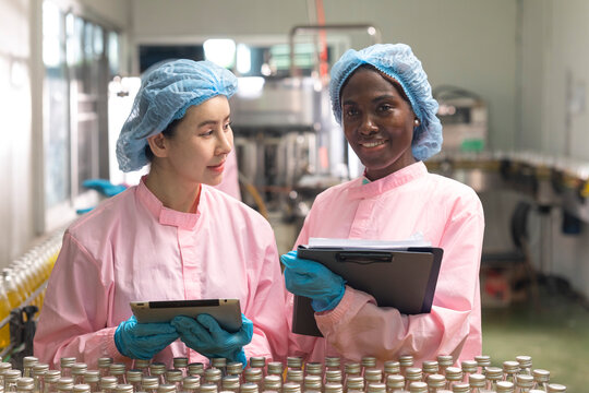 Asian and black factory worker inspect line product with tablet in beverage factory. Food and drinks Industry workers. 
