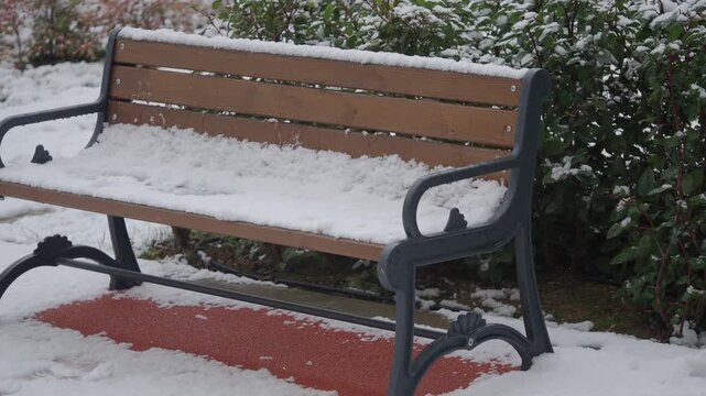 Wooden park bench covered in fresh snow during cold winter day