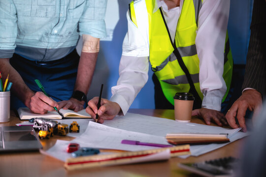 Construction management team discussing building layout paper on desk. Close-up hand while write shot. Concept of project planning, schedule of work, Brainstorm ideas and find solutions to problems.