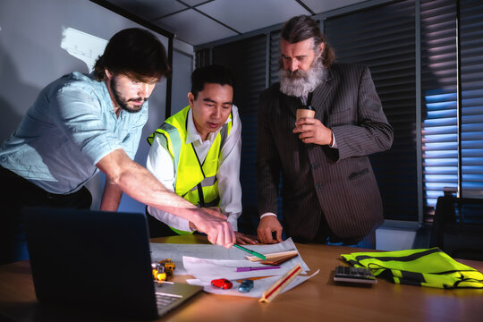 Construction management team discussing building layout paper on desk with senior investor in boardroom. Concept of project planning, schedule of work, brainstorm ideas and find solutions to problems.