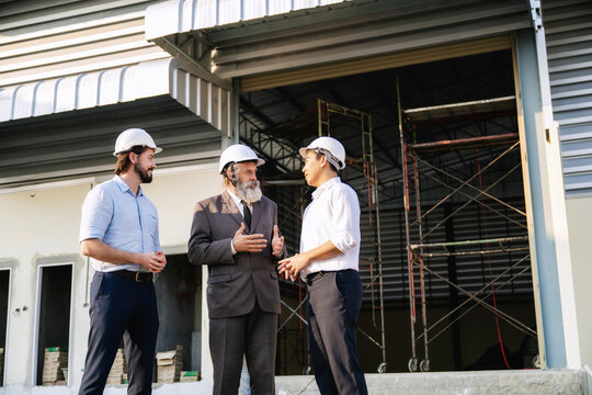 Senior manager discussing with construction engineers in progress of work for warehouse structure. Concept of real estate construction warehouse project, structural engineering progress evaluation.