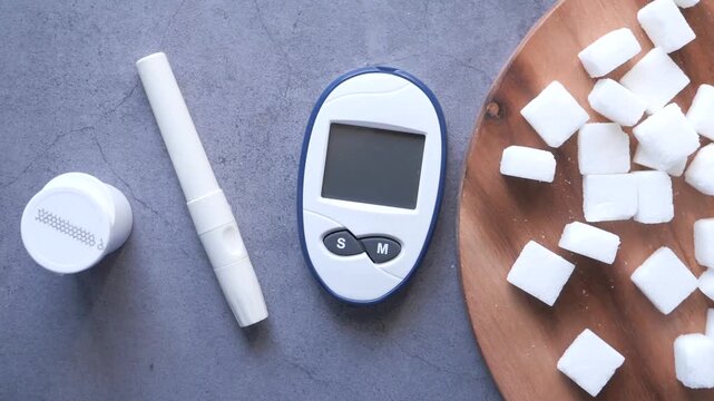 Close up of glucometer and sugar cubes on table, diabetes management concept
