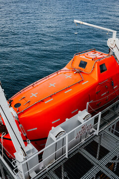 Orange Lifeboat Secured on Davit Launching System of Commercial Vessel