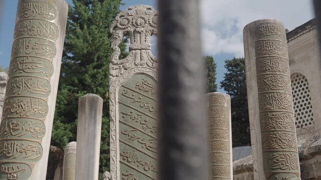 Ancient tombstones with ornate Arabic inscriptions stand in a serene garden setting