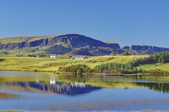 Houses and mountains reflected in a shallow loch, Quiraing, Isle of Skye, Hebrides, Scotland, United Kingdom