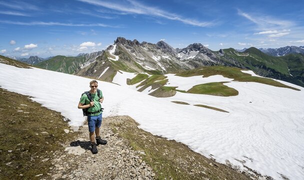Hiker, mountaineer on the hiking trail, Heilbronner Weg, in the background old snow fields and mountain panorama with summit of Gro&szlig;er Krottenkopf and Ramstallkopf, Allg&auml;u Alps, Allg&auml;u, Bavaria, Germany