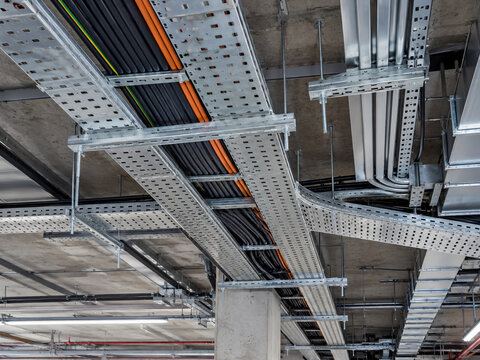 Cable trays and electrical conduits beneath an industrial ceiling