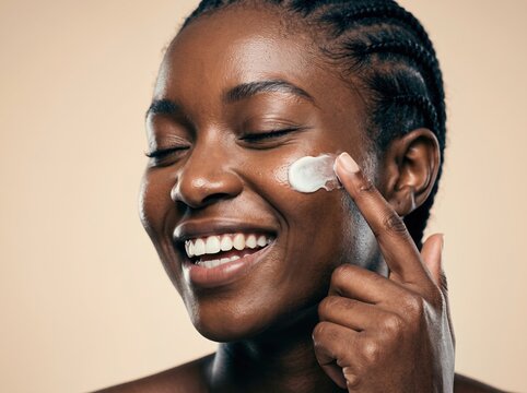 Happy African American Woman Applying Moisturizing Face Cream for Skincare Routine