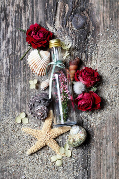 Flat lay composition on a wooden pier featuring seashells, dried flowers, sand, and romantic love letters. Conceptual background for book covers, nostalgia, summer romance, and memories.