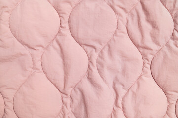Obraz premium Pink quilted fabric fills closeup frame with stitched organic shapes and soft texture. Textile surface offers gentle material detail for apparel design, bedding concepts and fabric marketing.