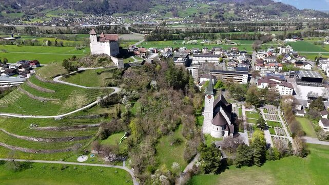 parish church clock tower gutenberg castle hilltop vineyard terraces green slopes balzers mals town rooftops rhine valley farmland snowcapped alpine peaks aerial view drone footage liechtenstein