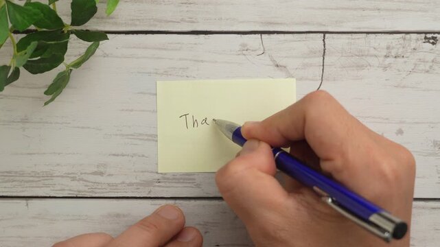 俯瞰撮影で付せん紙にボールペンで「Thank you」の文字を書く