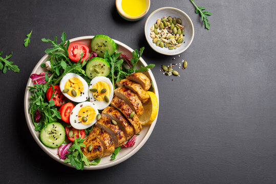 High protein lunch bowl with chicken, eggs and vegetable salad.