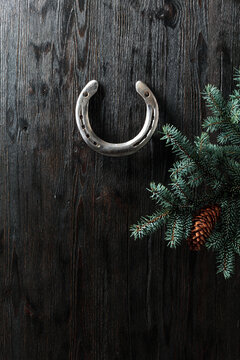 Old horseshoe and spruce branches on a wooden background.