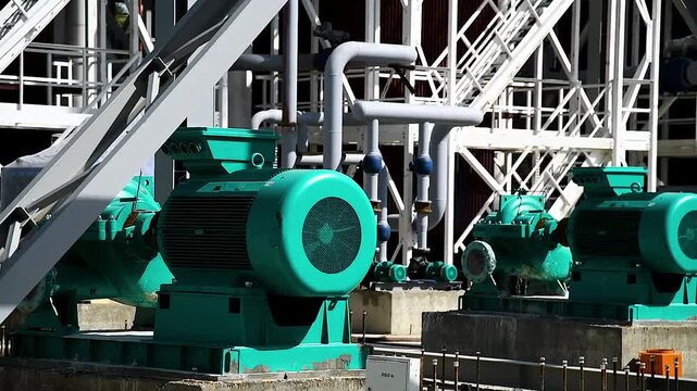 Several large new green electric motors mounted on concrete bases.