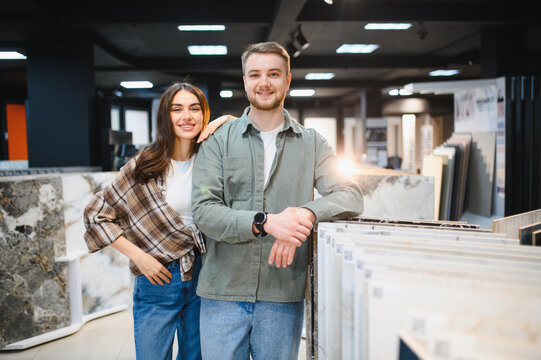Happy couple renovating kitchen choosing tiles in showroom