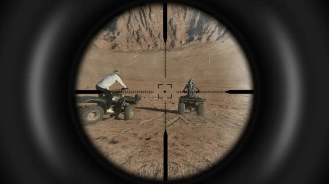 Sniper rifle scope view tracking a person riding an ATV quad bike in the desert landscape