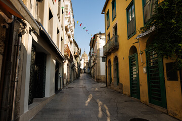 Fototapeta premium Narrow Cobblestone Street with Historic Buildings and Distant Be