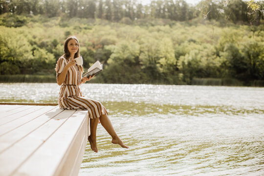 Enjoying a tranquil moment by the lake with a book and a warm drink
