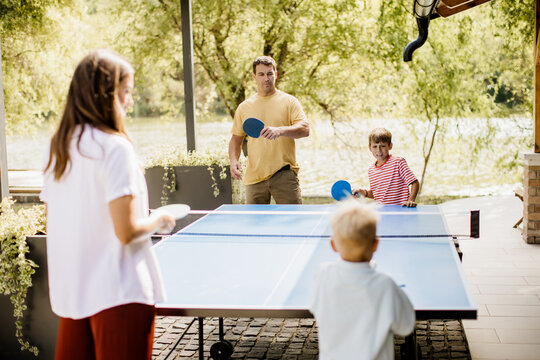 Family fun with table tennis by the lakeside on a sunny afternoon
