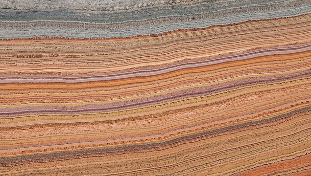 Close-up of layered sedimentary rock with vibrant orange, cream, and brown hues