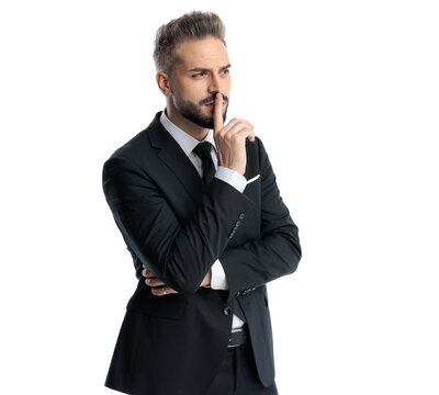 Serious man holding finger to lips making a silence gesture